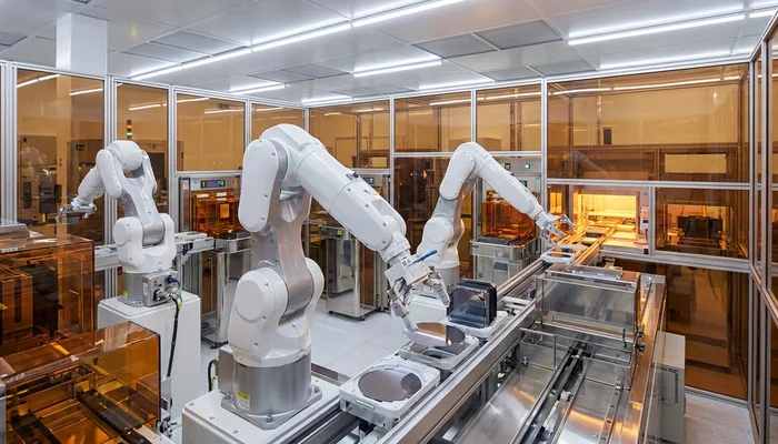 Interior de uma sala limpa industrial com braços robóticos manuseando componentes eletrônicos.